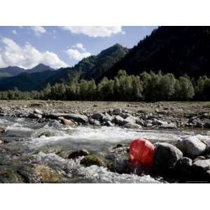 Red Paper Lantern Washed Up against Rocks in a River, Qinghai, China 