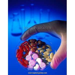  Gloved hand holding a dish of capsules andamp;amp; pills 